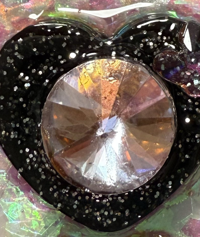 Close-up of a decorative item with a large crystal and black glittery bow