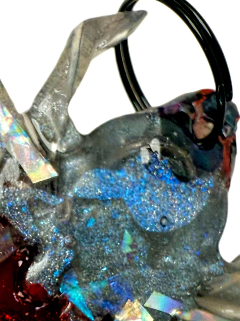 Close-up of a resin dog jewel tag with red, blue, and silver holographic colour and glitter 