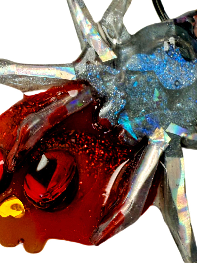 Close-up of a resin dog jewel tag with red, blue, and silver holographic colour and glitter 